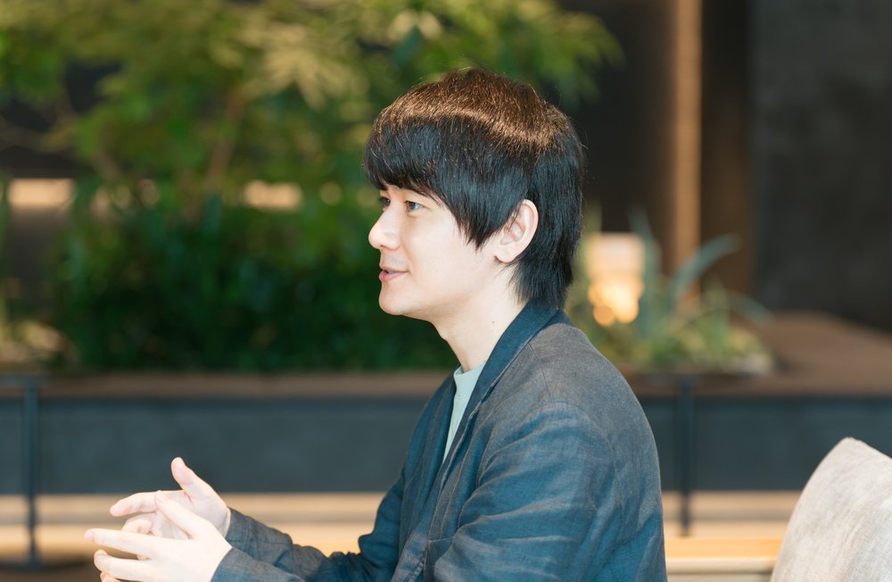 Close-up focusing on Takashima's profile as he gestures during the conversation.
		