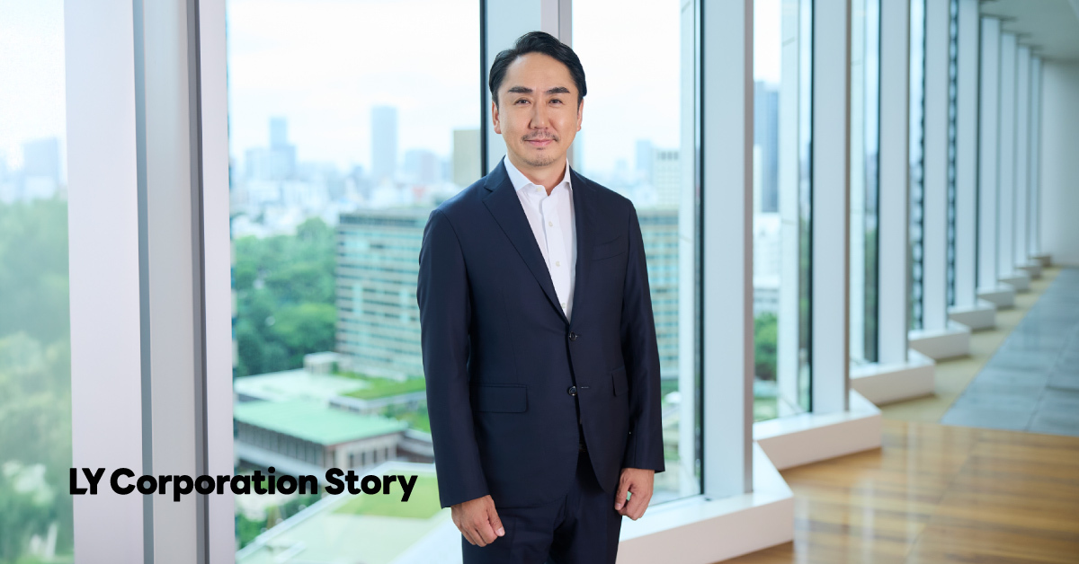 In an indoor setting by the window, CEO Idezawa, dressed in a suit, is standing and smiling. The text LINE Yahoo Story is displayed in the lower left corner.