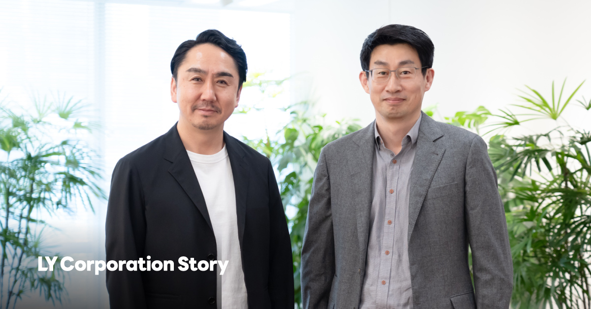 CEO Idezawa and CPO Shin stand side by side in a bright office with plants, facing the camera.