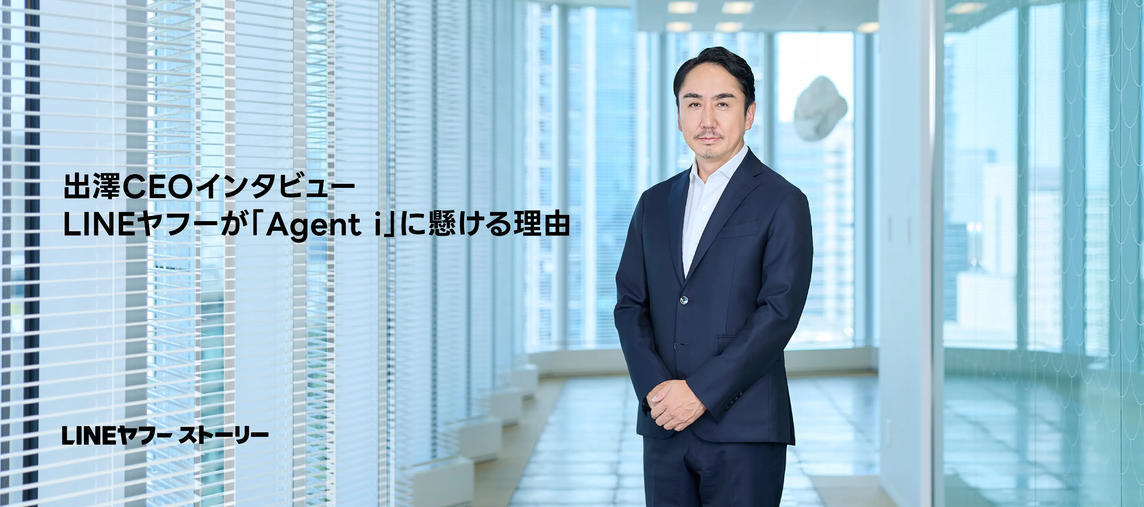 明るいオフィスの窓際でスーツ姿で立つ出澤CEOの写真。「出澤CEOインタビュー LINEヤフーが『Agent i』に懸ける理由」という見出しと、媒体名「LINEヤフー ストーリー」の文字が配置されている。