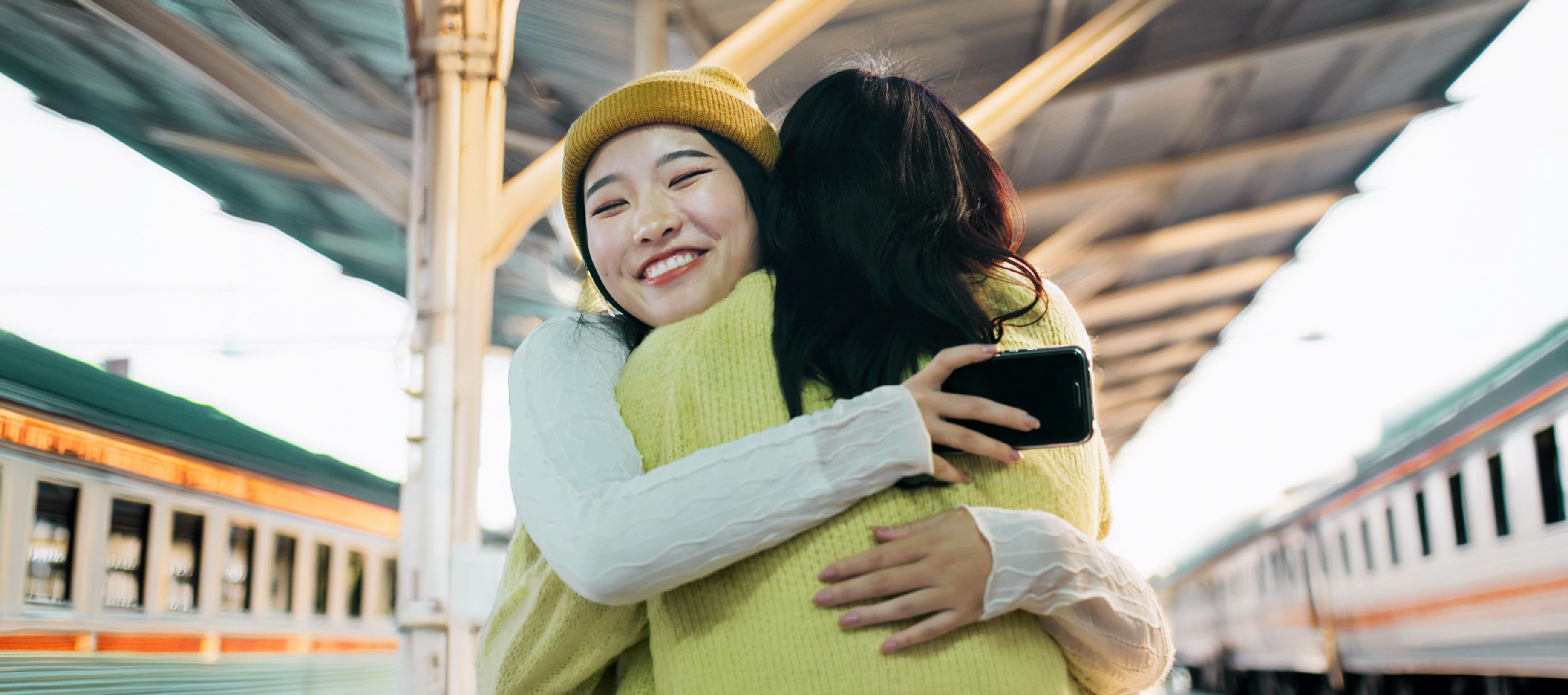 駅のホームで、黄色のニット帽をかぶり、心からの笑顔で大切な人と抱き合う女性。中央にはLINEヤフーのミッション「WOW Our Users!」のテキストが配置されています。
