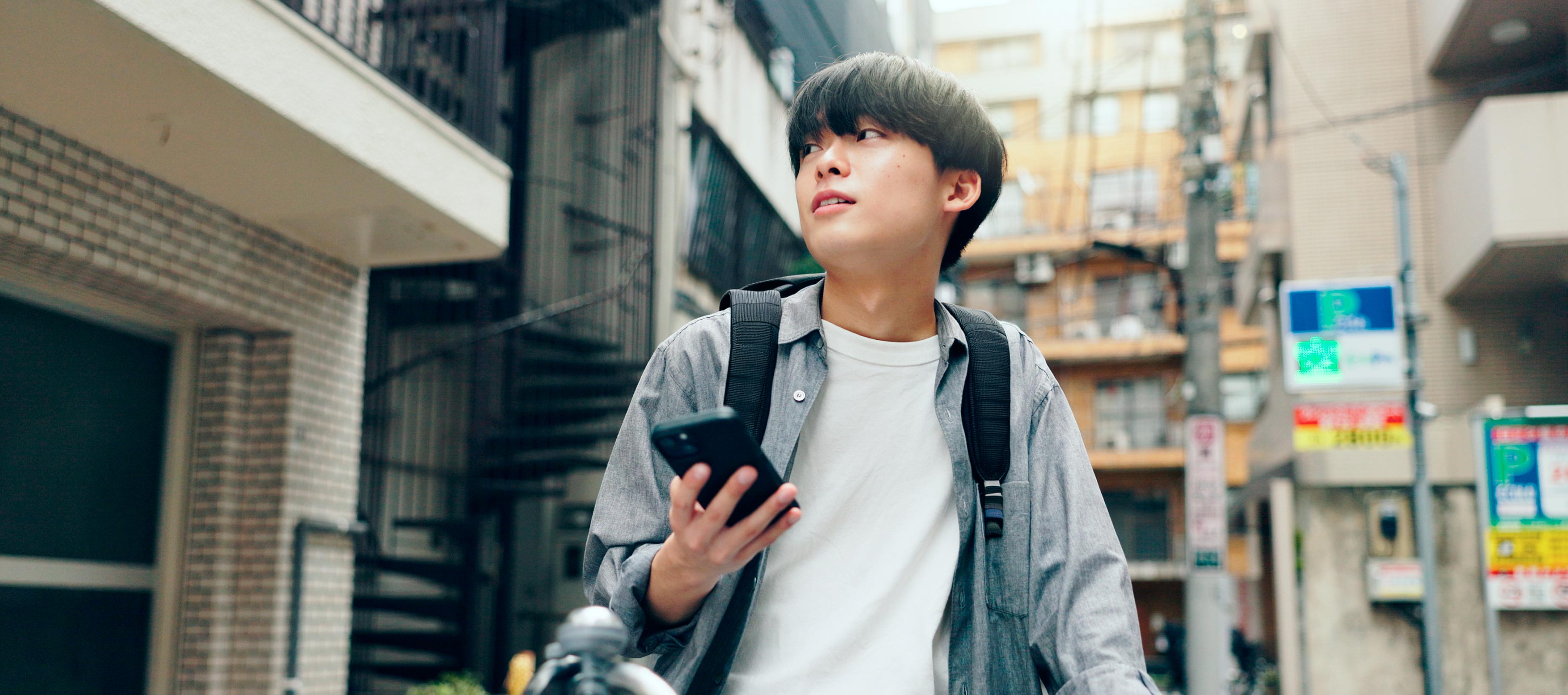 街角でスマートフォンを手に、少し遠くを見つめる男性。中央にはLINEヤフーのミッション「WOW Our Users!」のテキストが配置されています。