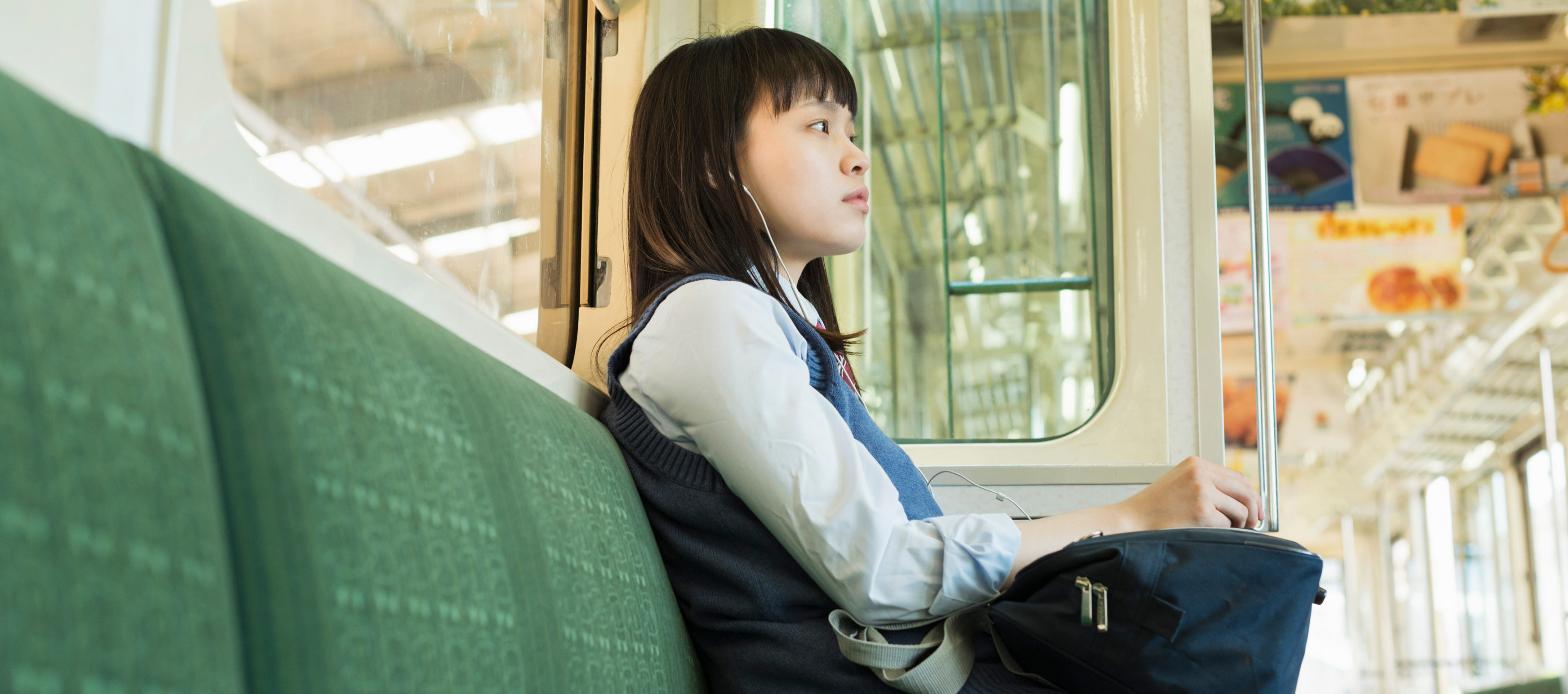 電車の座席に座り、イヤホンをして静かに窓の外の景色を眺める女性。中央にはLINEヤフーのミッション「WOW Our Users!」のテキストが配置されています。