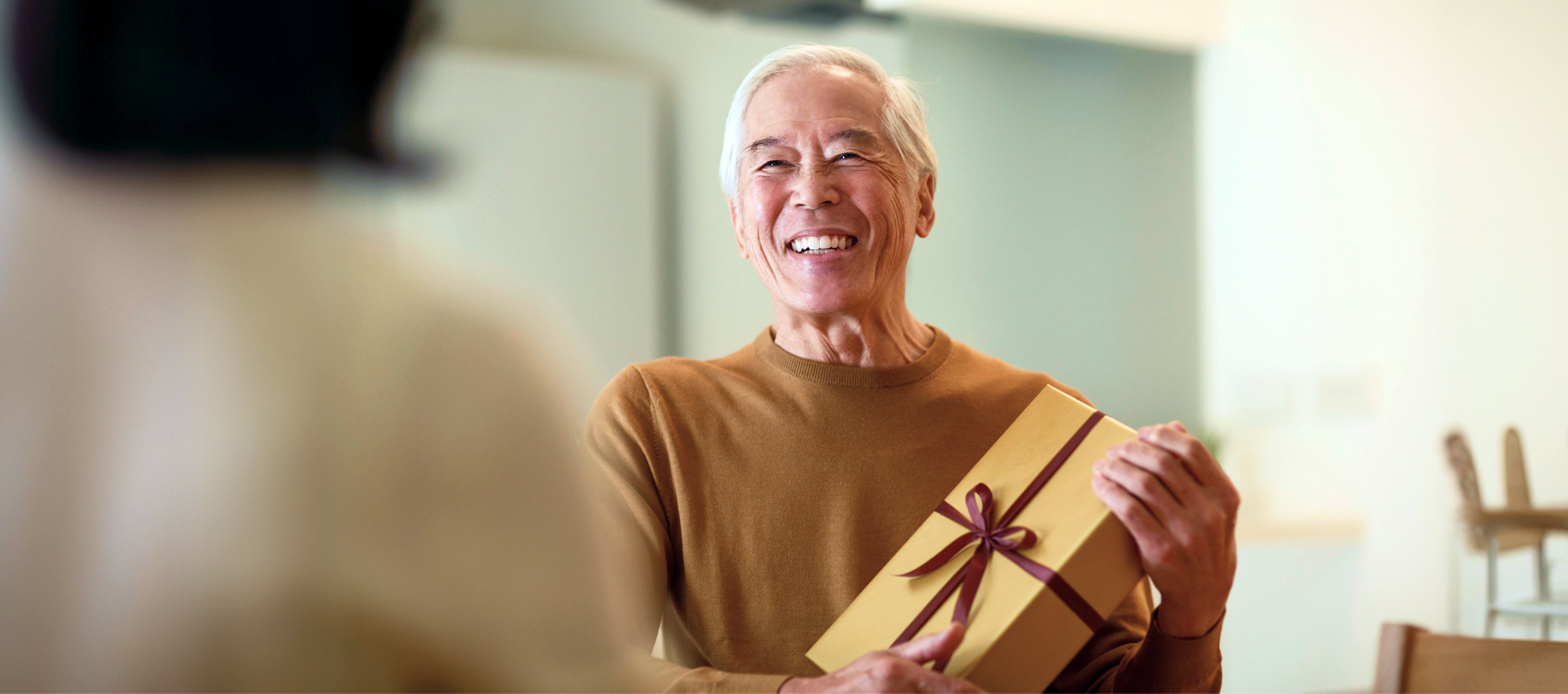 リボンのかかったプレゼントを大切そうに抱え、穏やかな笑みを浮かべる高齢の男性。中央にはLINEヤフーのミッション「WOW Our Users!」のテキストが配置されています。