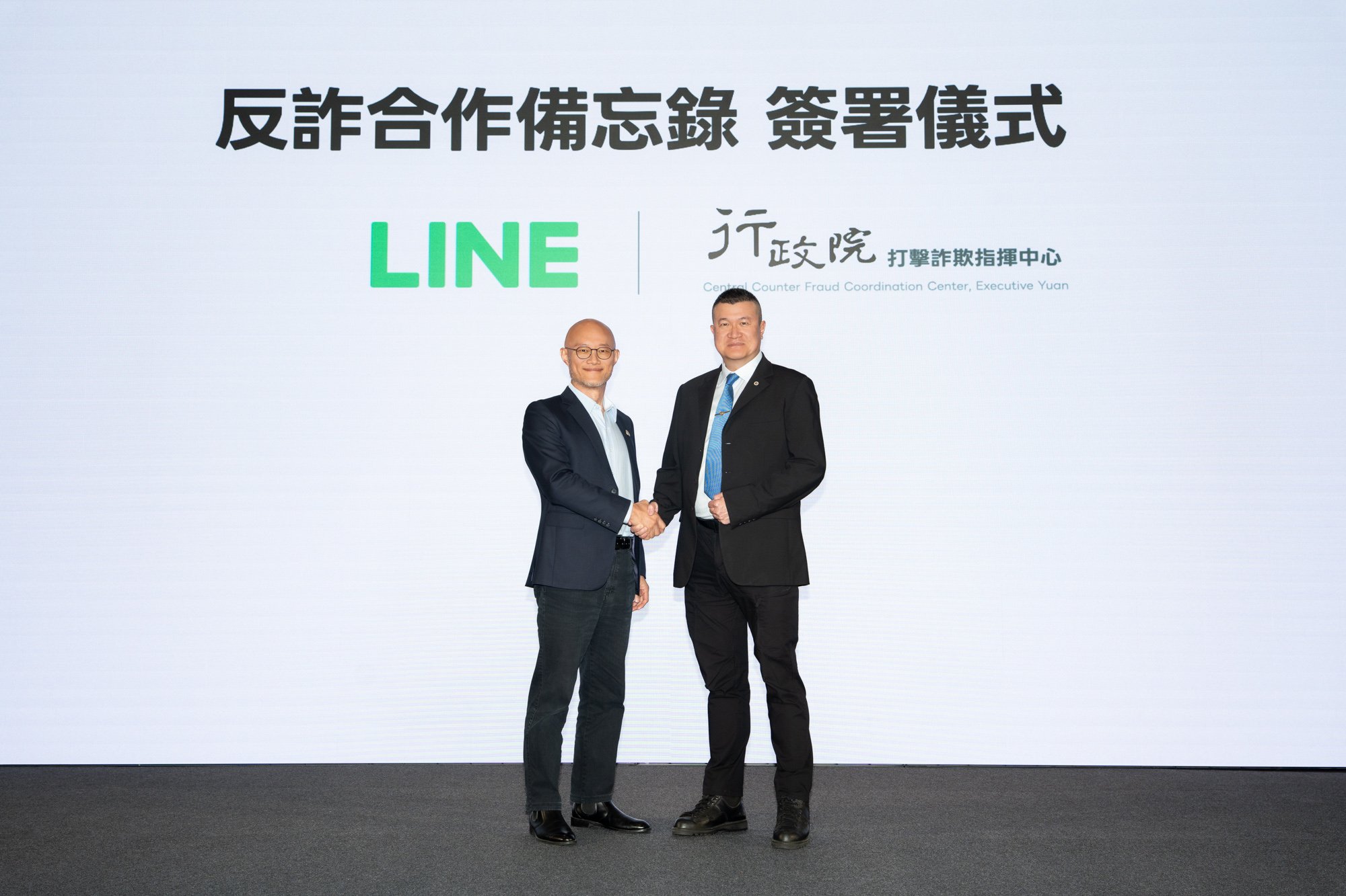 握手するLINE TaiwanのCEO Roger Chen氏(右）と行政院 詐欺対策指揮センター Sawyer Mars氏(左)