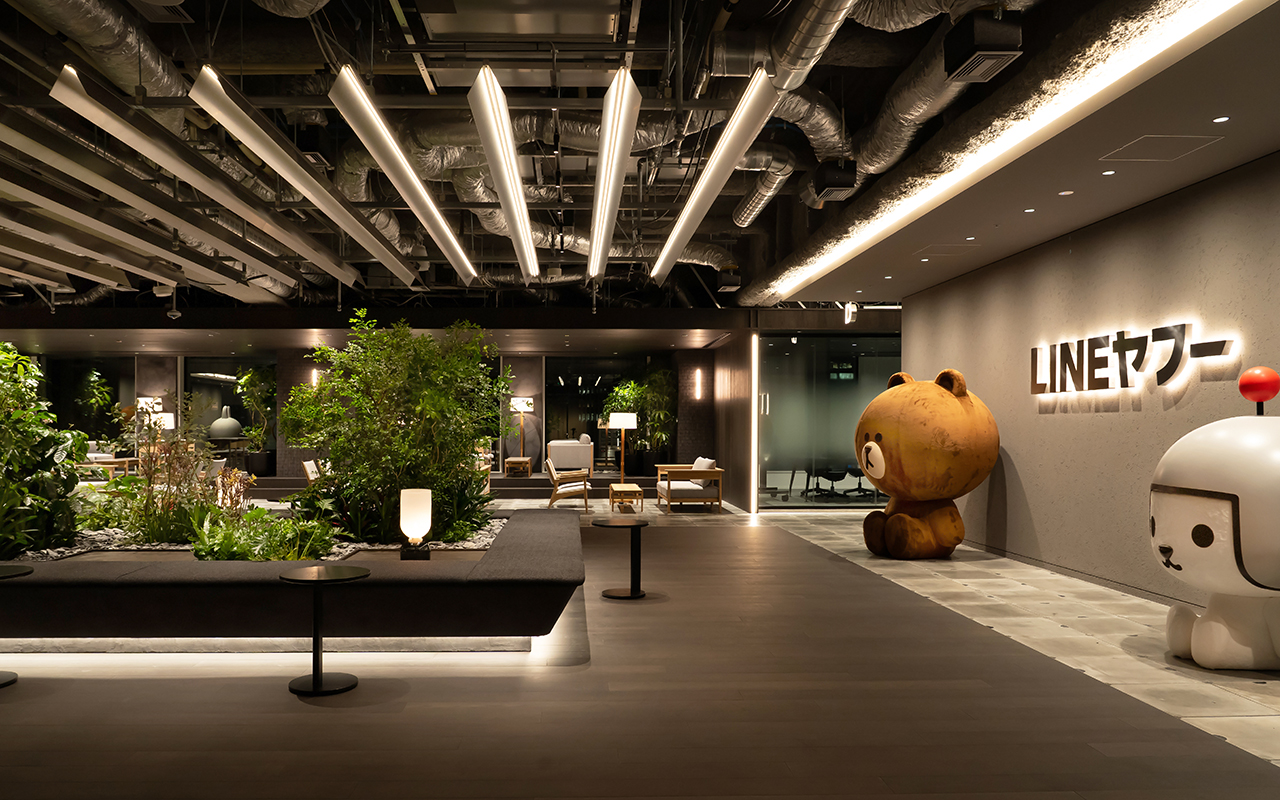 LINEヤフーのロゴとキャラクターが配置された、植物のある落ち着いた雰囲気のオフィスラウンジ