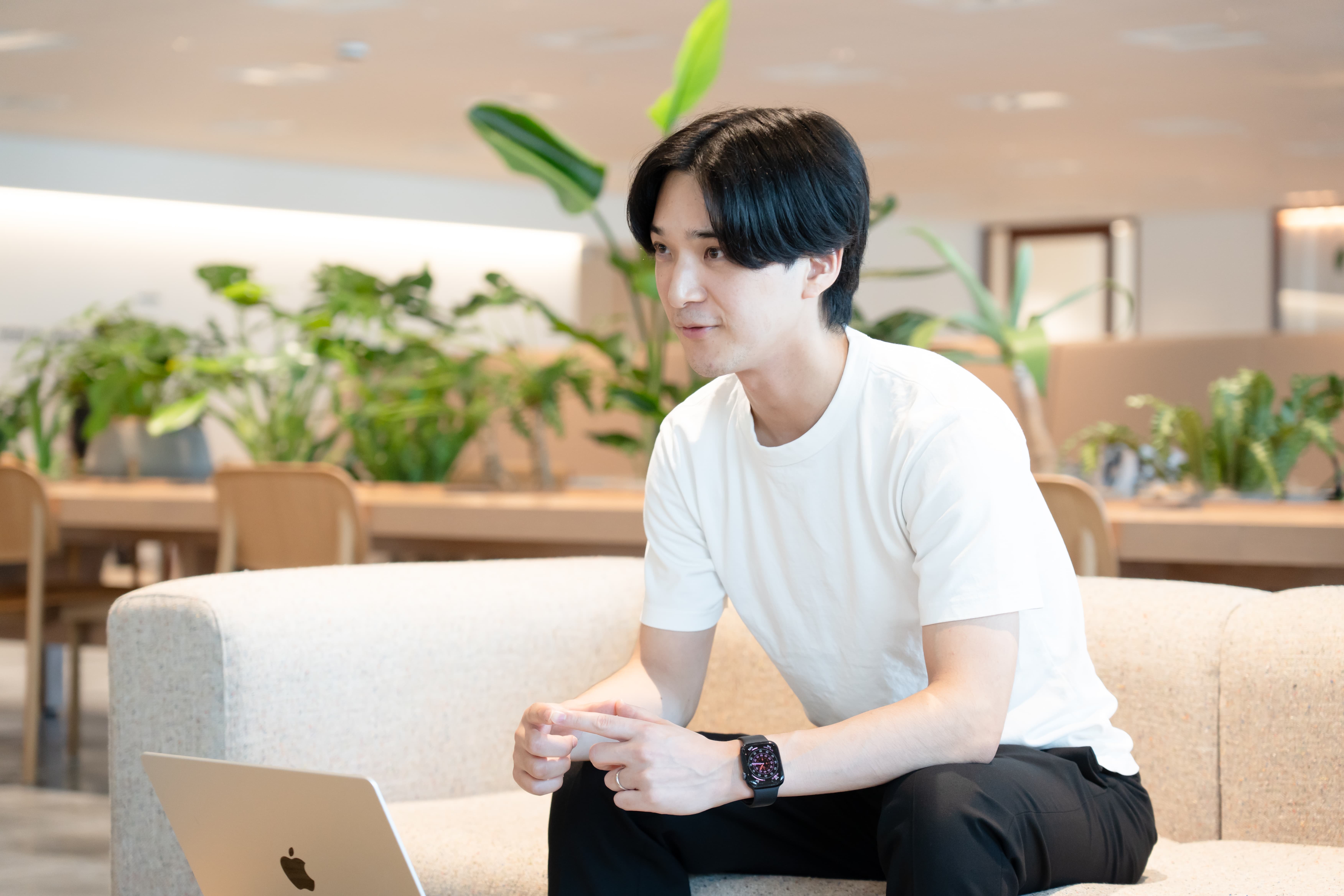 ソファに座り、身振りを交えながら話す中野修平さんの写真。背後に観葉植物が並んでいる。