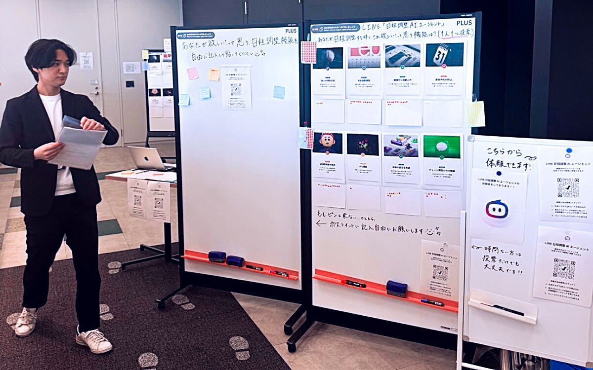 日程調整AIエージェントの検証ボードの前で説明する中野修平さんの写真。