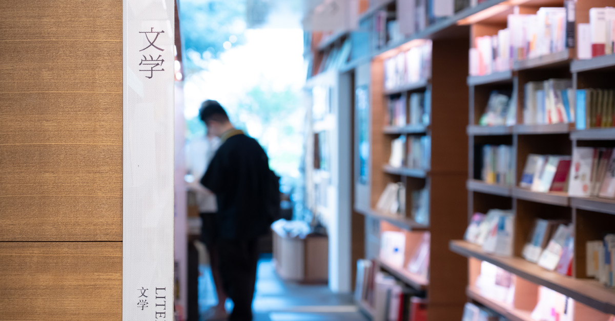 代官山 蔦屋書店の店内写真。書棚が並ぶ通路の手前に文学コーナーのサインが立ち、奥には来店者の姿が見える。