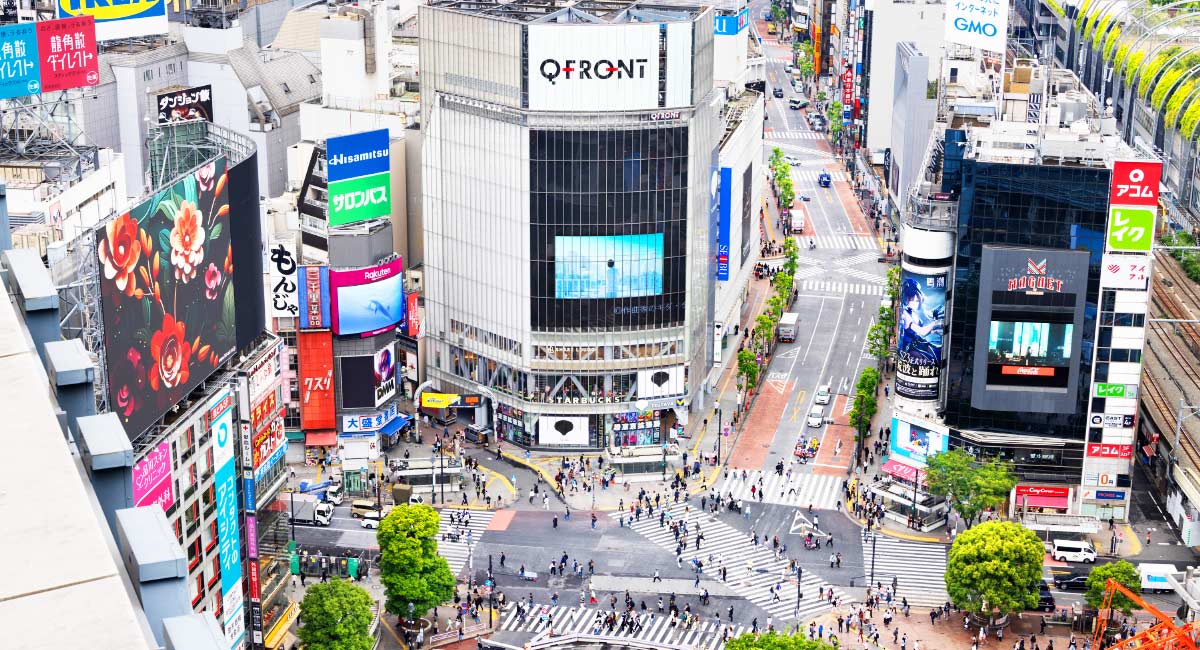 渋谷スクランブル交差点と周辺のビル群を高所から見下ろした写真。中央にはQFRONTが見え、都市のにぎわいが広がっている。
