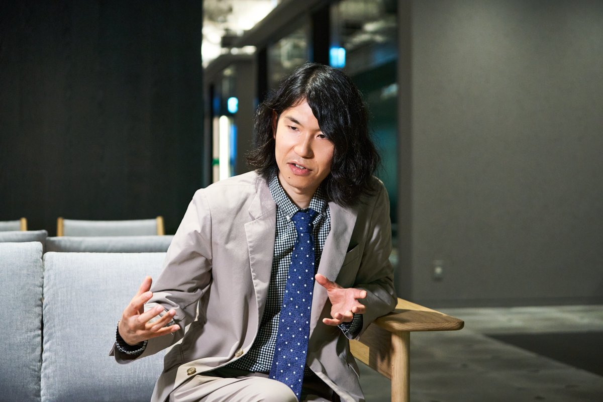 ソファに座った樋口恭介さんが身ぶりを交えながら話している写真。
