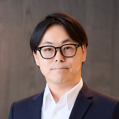 椅子に腰掛けて身ぶりを交えながら話すLINEヤフーCDO・菅谷聡さんの写真。ネイビーのスーツに白いシャツを合わせ、明るい表情で取材に応じている。
