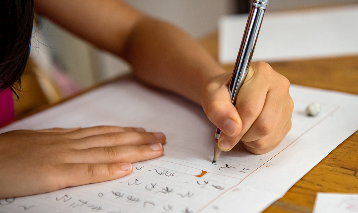 子どもが鉛筆で文章を書いている様子です。手元に集中し、丁寧に書き込んでいます。