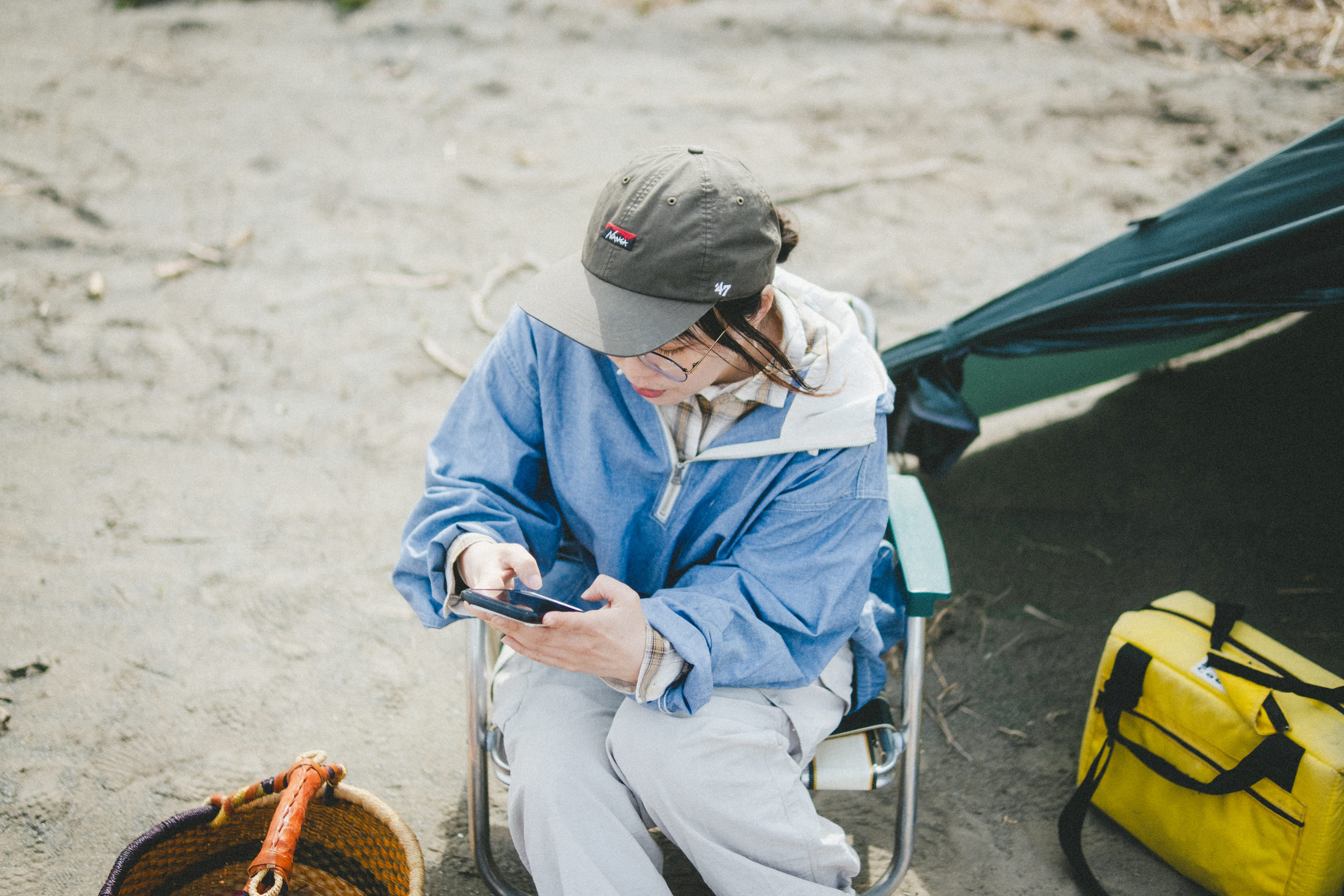 屋外のキャンプ場で、アウトドアチェアに座ったこいしさんを上から捉えた写真。