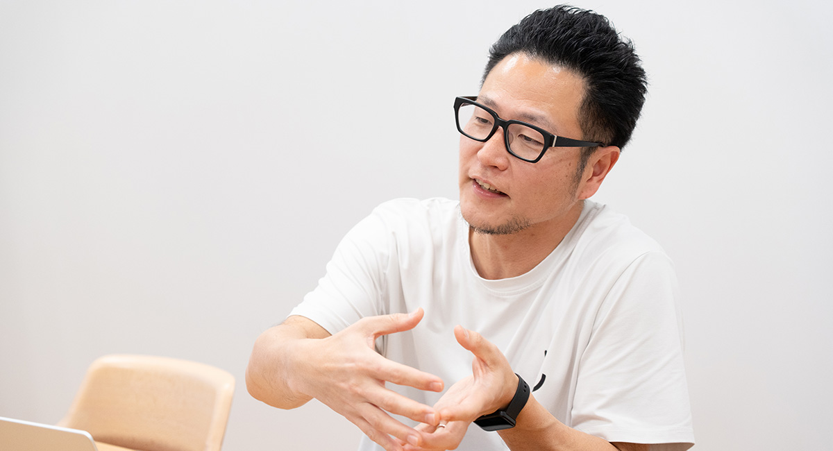 男性が手を使いながら説明している様子で、真剣な表情をしています。