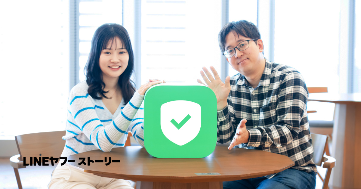 ソヨンと海老原のバストショット。2人は両手でテーブル中央に置かれた緑色のアイコン型オブジェに触れている。左下には「LINEヤフーストーリー」という文字が表示されている。
