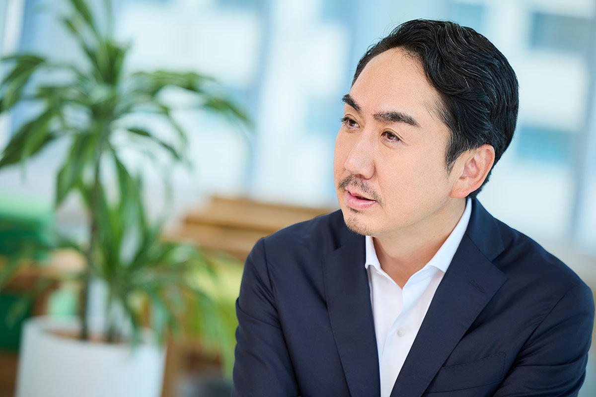 スーツ姿のCEO出澤が、横を向いて話している写真