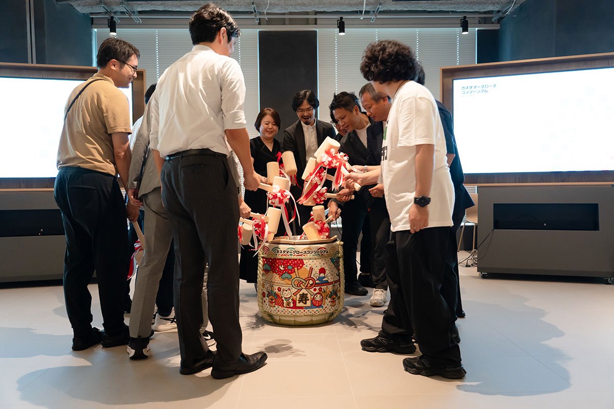 カスタマーグロースコンソーシアムの参画企業メンバーが、発足会のステージで木づちを手に鏡開きを行っている様子。