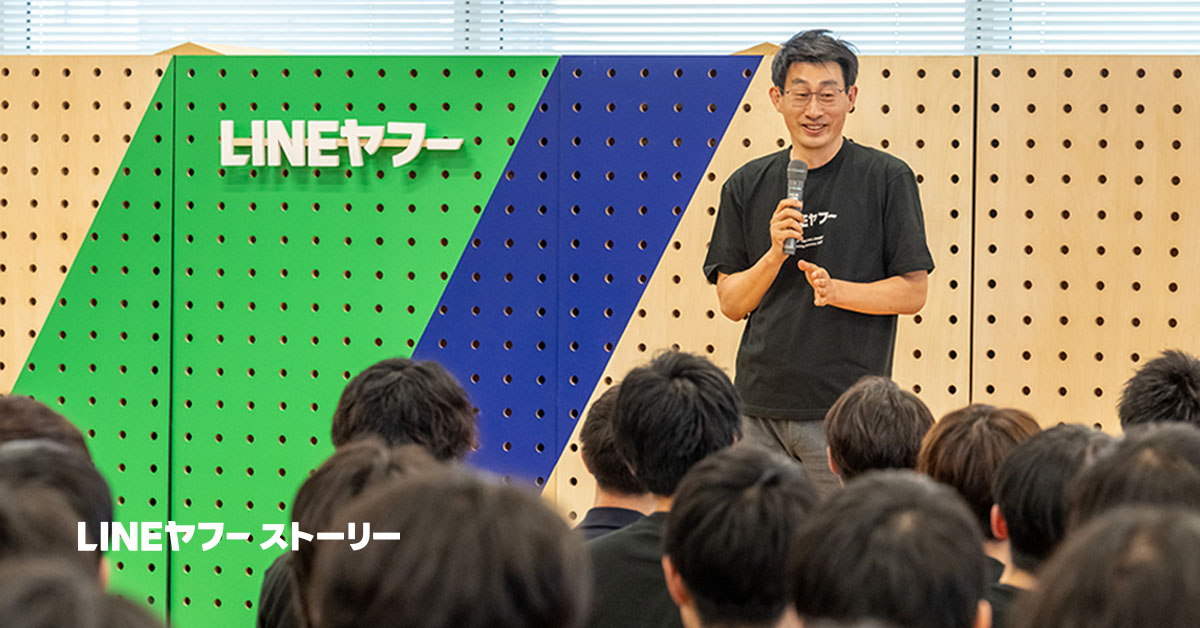 LINEヤフーの入社式において、CPOが新入社員に向けてスピーチを行っている。背景には「慎ジュンホ」と書かれたスクリーンがあり、参加者たちは真剣に耳を傾けている