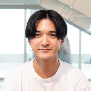 ソファに座って笑顔を見せる中野修平さんの写真。