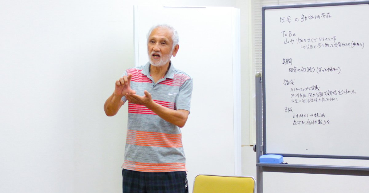室内のホワイトボードの前で、身振りを交えて話すベテラン猟師の武井正和さん