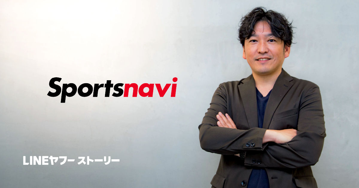 グレーの壁の前で腕を組む男性、小用CEOが笑顔で立っている。黒髪で少しウェーブがあり、濃い色のジャケットを着ている。左側には赤と黒の「Sportsnavi」ロゴ、左下には白字で「LINEヤフー ストーリー」と表示されている。