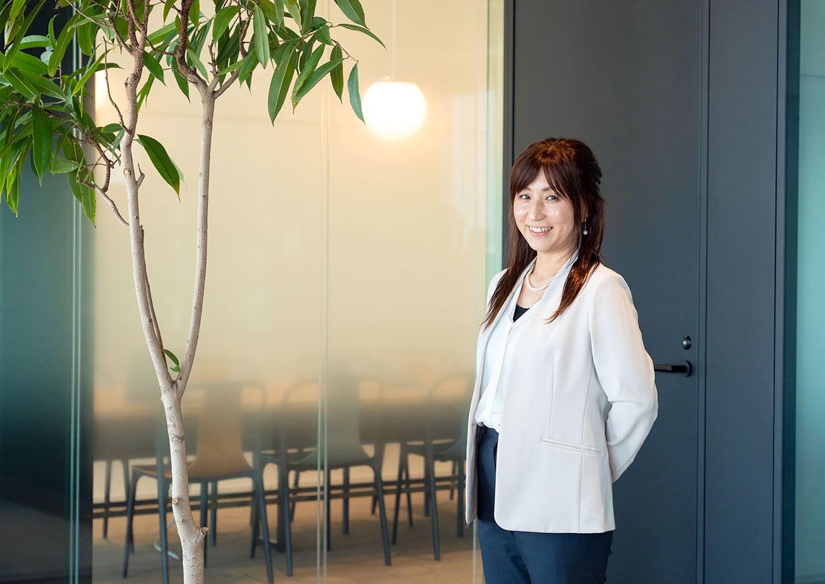 正木CEOがテーブルに肘をついて微笑んでいます。シンプルな背景で、カジュアルなビジネスシーンを感じさせます。