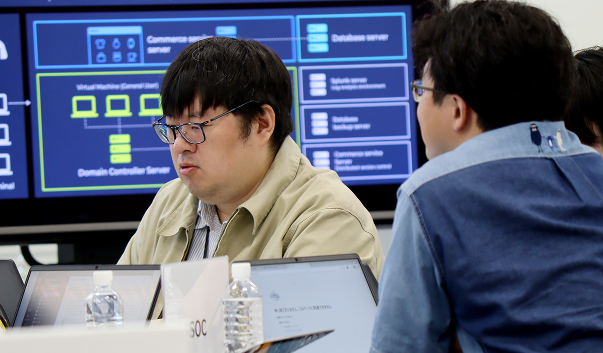 会議室で2人の男性がノートパソコンを前に打ち合わせをしている様子。