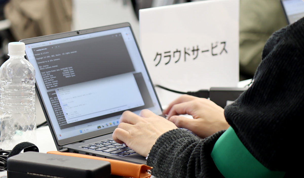 会議室で人物がノートパソコンを操作している手元の様子。