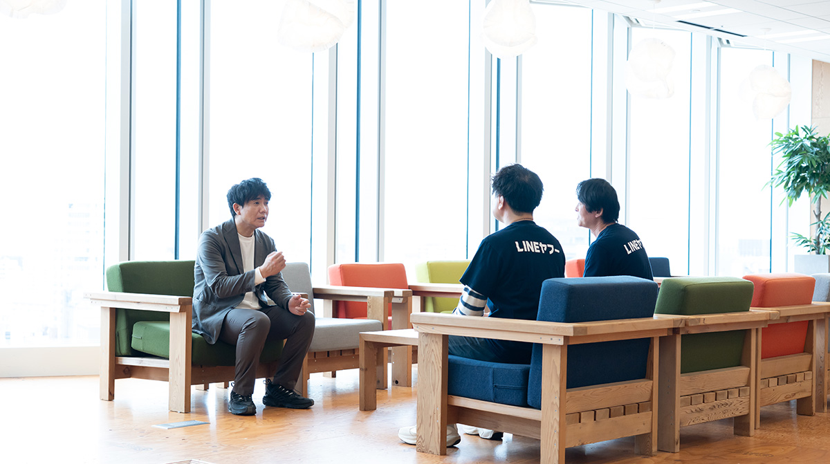 生井さん、水上さん、柴崎さんがオフィスのラウンジスペースで向かい合って座り、対話している様子の写真。
