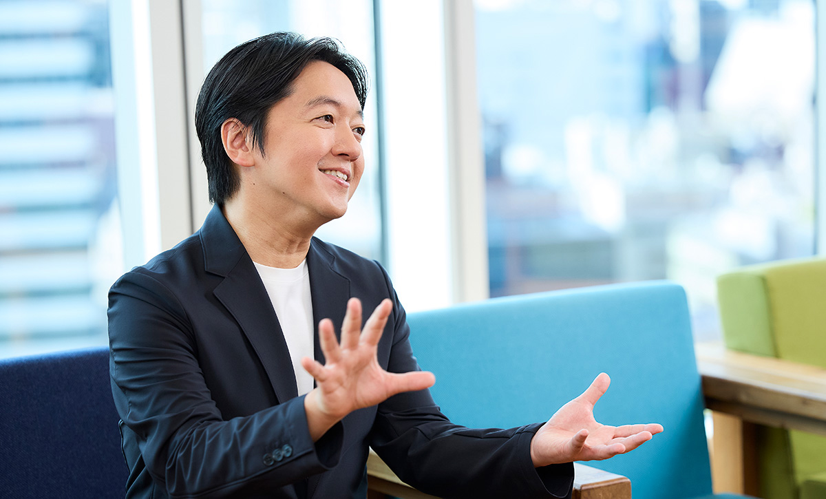 男性が笑顔で、手を広げて話している様子です。親しみやすい雰囲気が感じられます。