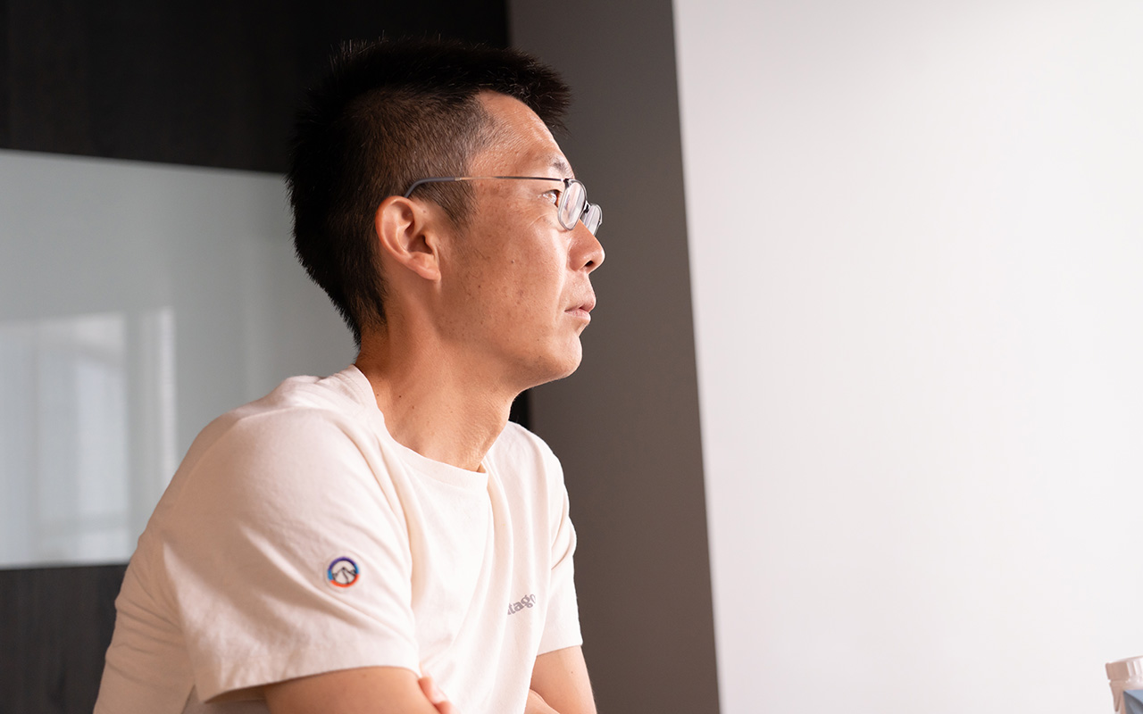 朝井が腕を組みながらやや前方を見つめ、落ち着いた表情で話を聞いている様子