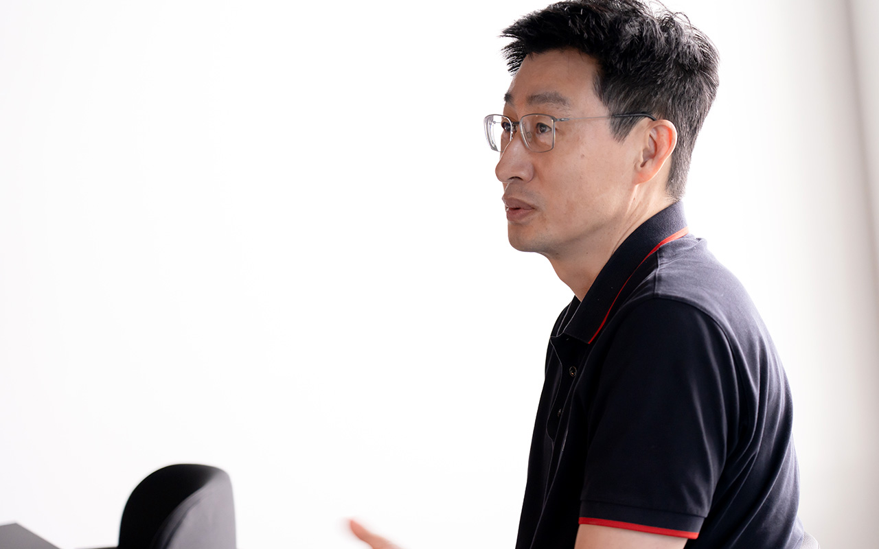 慎がやや前方を見つめながら真剣な表情で会話している様子