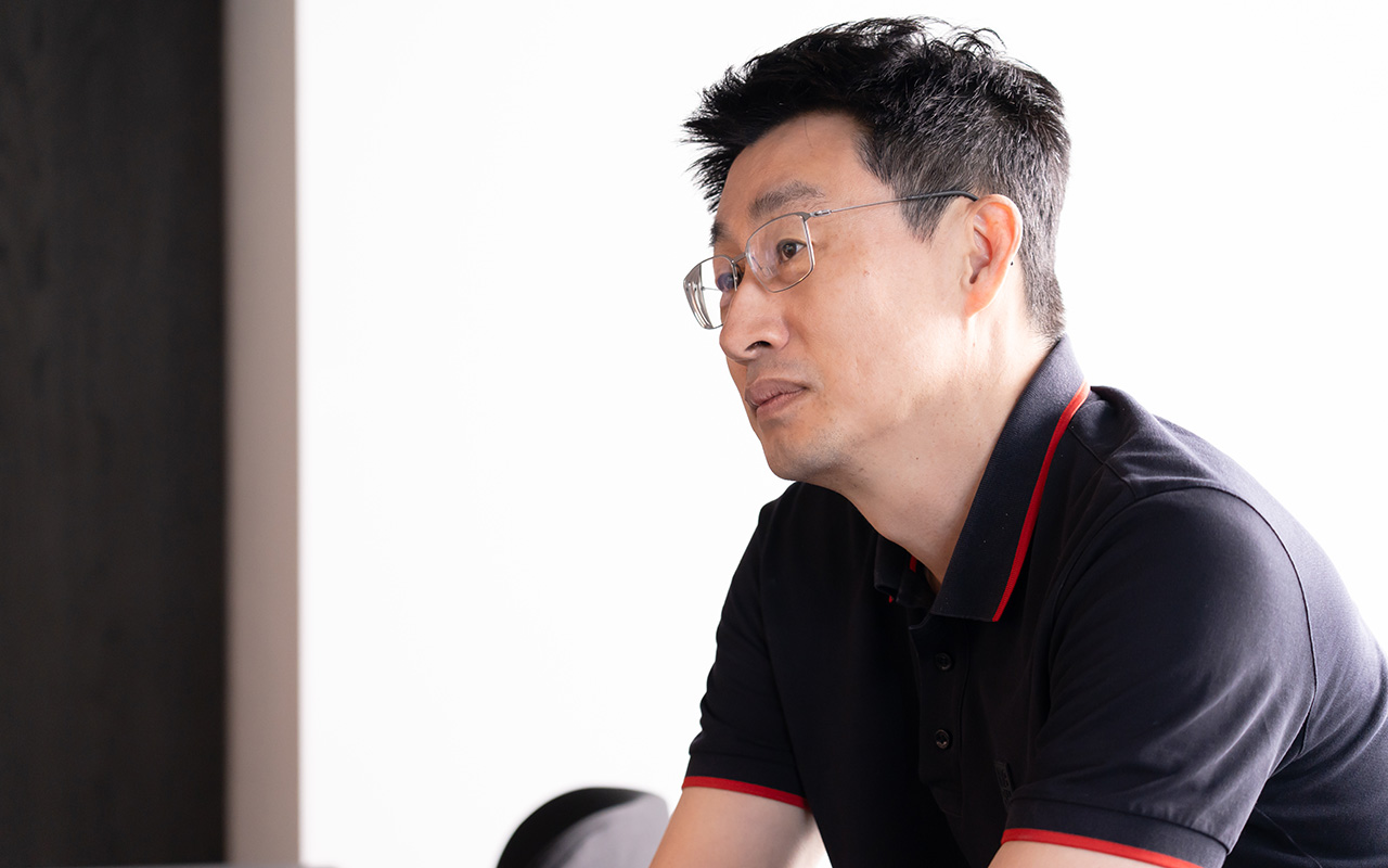 慎が体をやや前に傾けながら穏やかな表情で相手の話に耳を傾けている様子