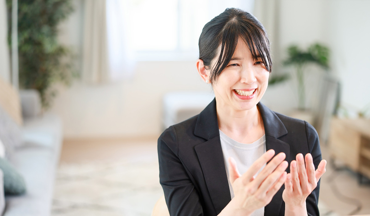 女性が笑顔で手を叩いています。背景には明るい部屋が広がり、リラックスした雰囲気が漂っています。