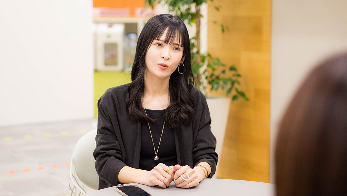 菅沼が向かい側の相手に向かって話している写真。