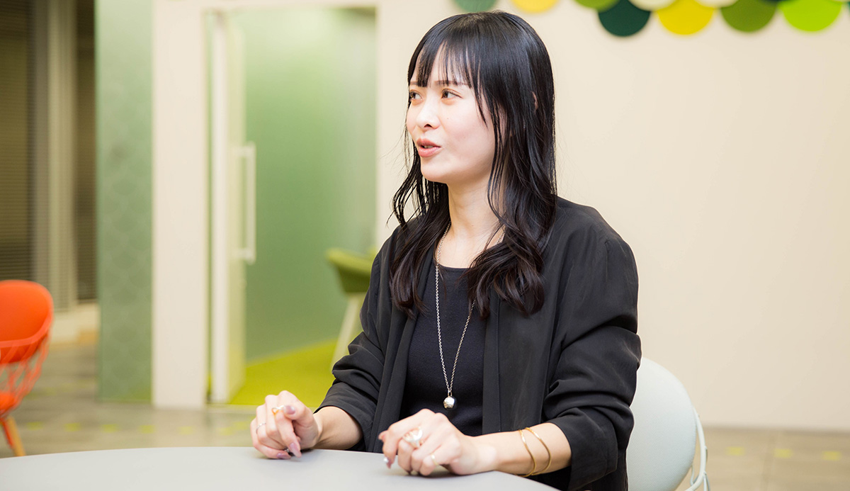 菅沼がやや横を向いて話している写真。