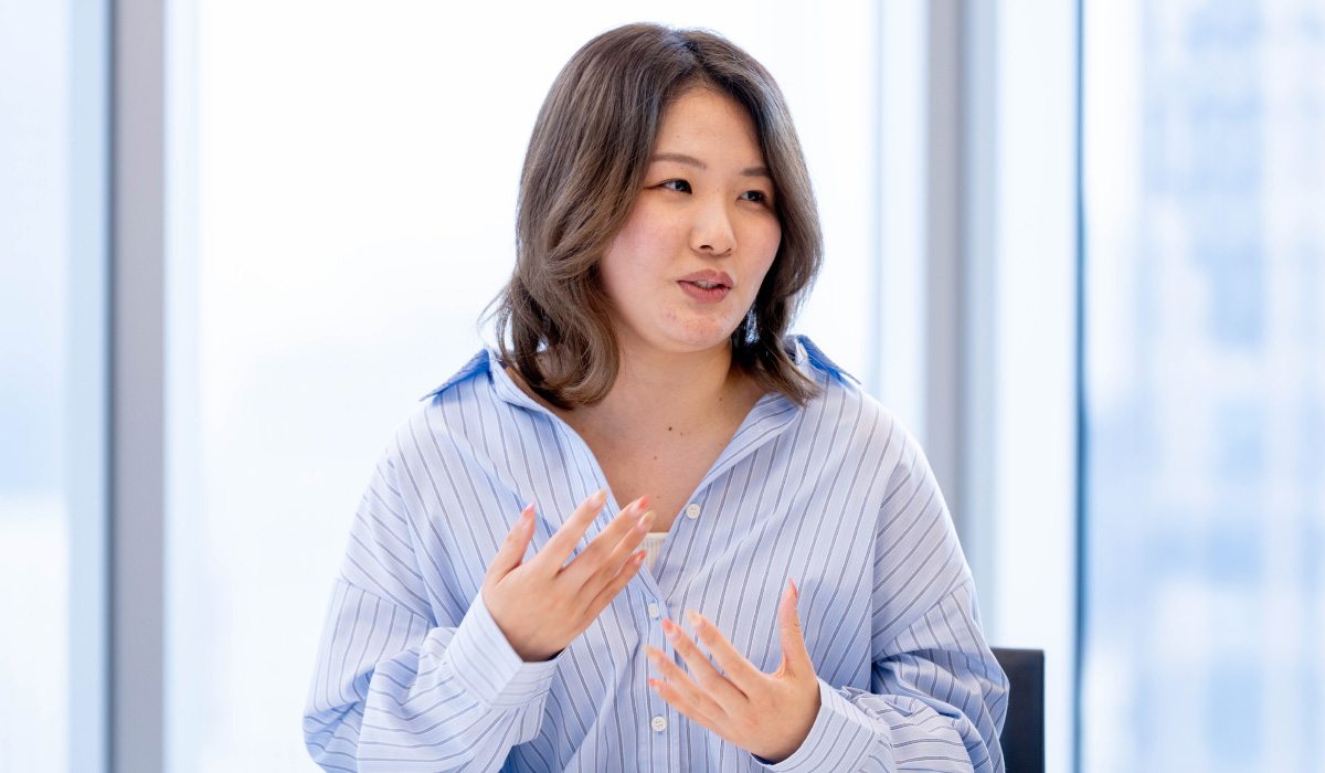 タスクフォースメンバーの一人が身ぶりを交えながら話している写真。明るい会議室で、自分の考えを丁寧に伝えている。