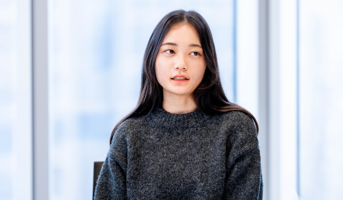 タスクフォースメンバーの一人が会議室で話している写真。窓際の席で前を向き、落ち着いた表情で語っている。