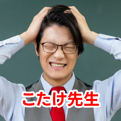 眼鏡をかけた男性・こたけ正義感さんが笑顔で写っているクローズアップ写真です。彼はグレーのベストと赤いネクタイを着用しています
