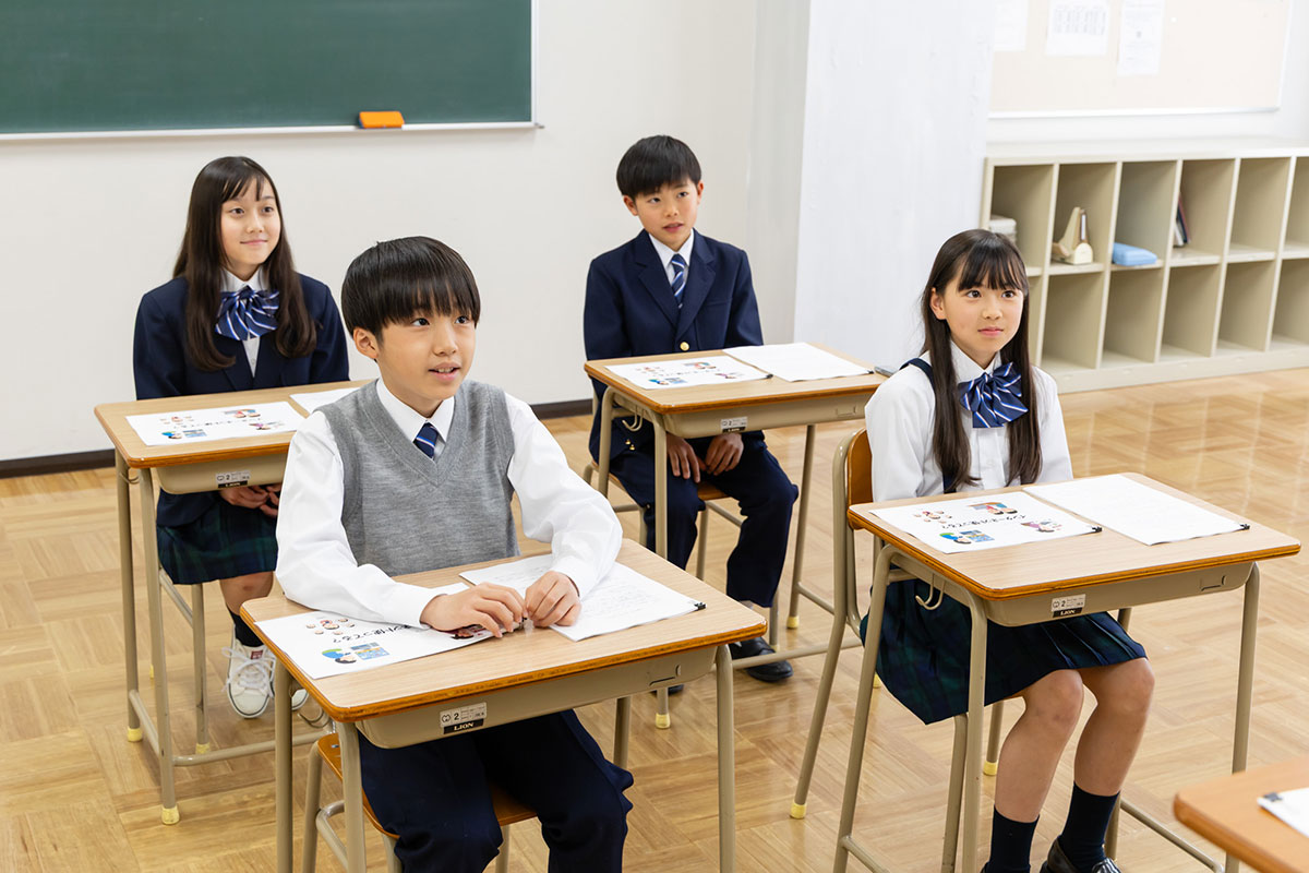 教室で生徒たちが机に座り、前を向いて授業を受けている様子です。皆、真剣に話を聞いています