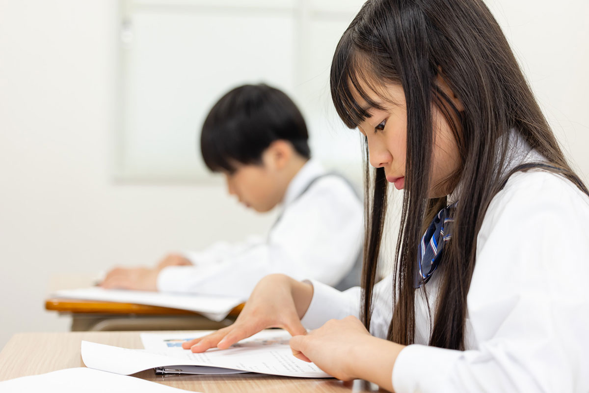 少女と少年が机に向かって集中して勉強している様子が映っています。彼らは真剣にノートを見ています