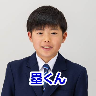 青いブレザーを着た若い男の子が笑顔で写っています。ネクタイも着用しています