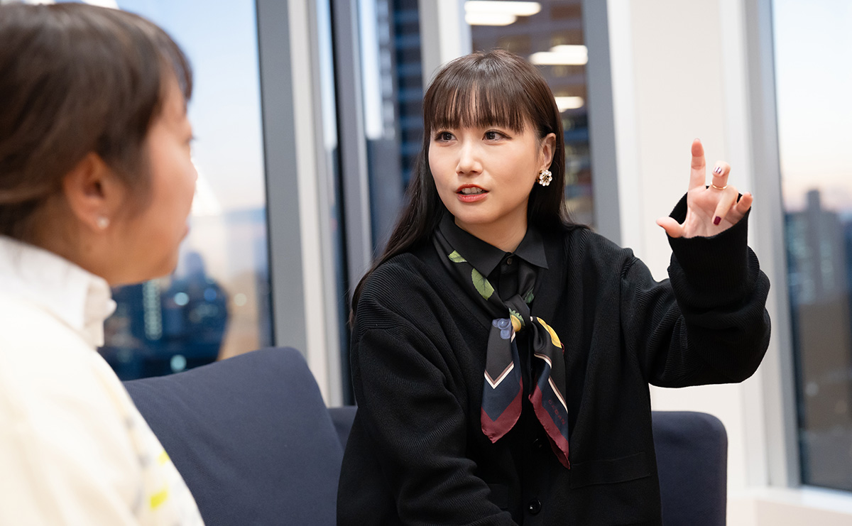 大塚愛さんと是近さんが向かい合って会話をしている様子。大塚愛さんは真剣な表情で話しながら右手を挙げている。