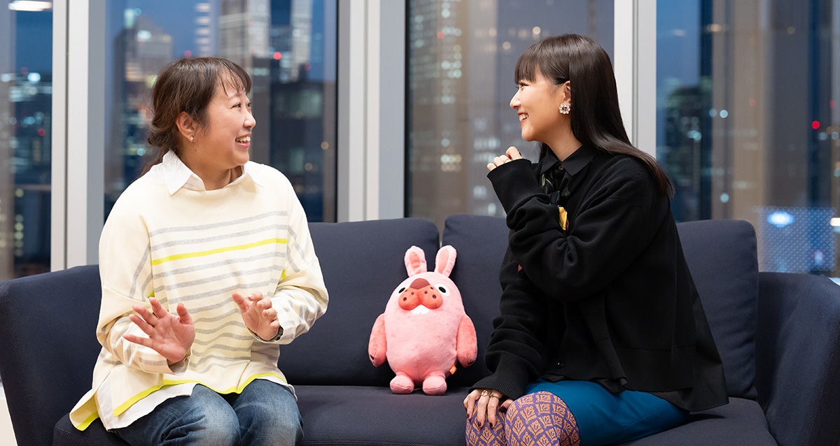 是近と大塚愛さんがソファに座って談笑している様子。二人の間にはピンク色のうさぎのぬいぐるみが置かれている。