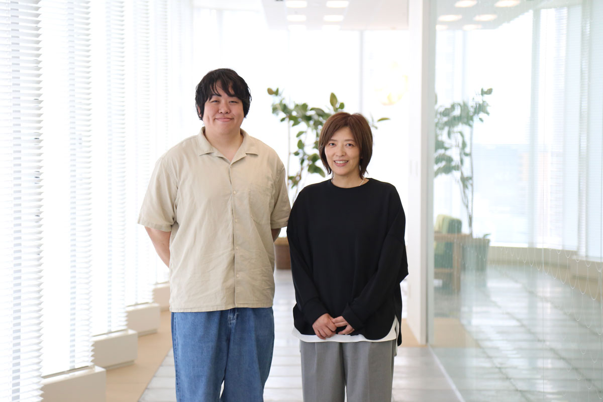 サービス担当者の山田と栗本。明るい光が差し込むオフィスでにっこりほほえむ