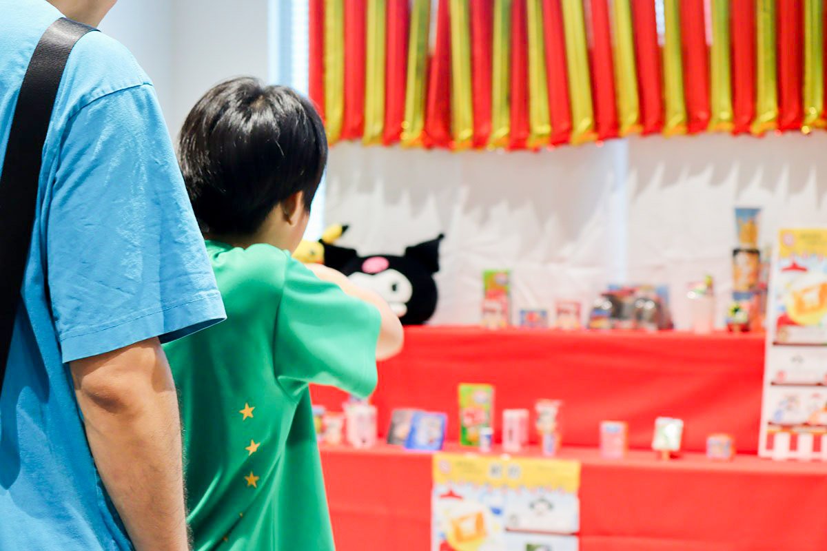 縁日ゲームの射的で、子どもが的を狙っている写真