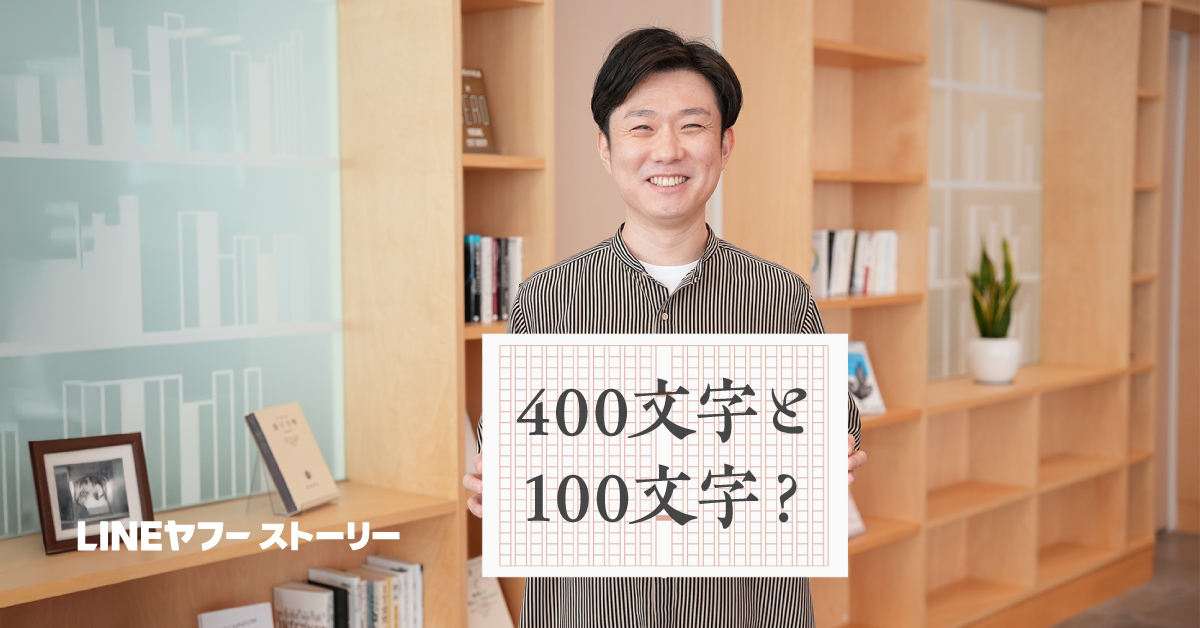 本棚の前で笑顔の男性が「400文字と100文字？」と書かれた紙を持っている写真です。背景に「LINEヤフーストーリー」と書かれています。
