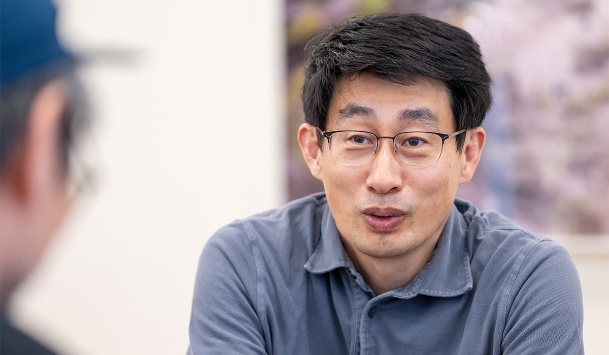 慎さんが誰かと対話している様子です。落ち着いた表情で、真剣に話を聞いているように見えます。