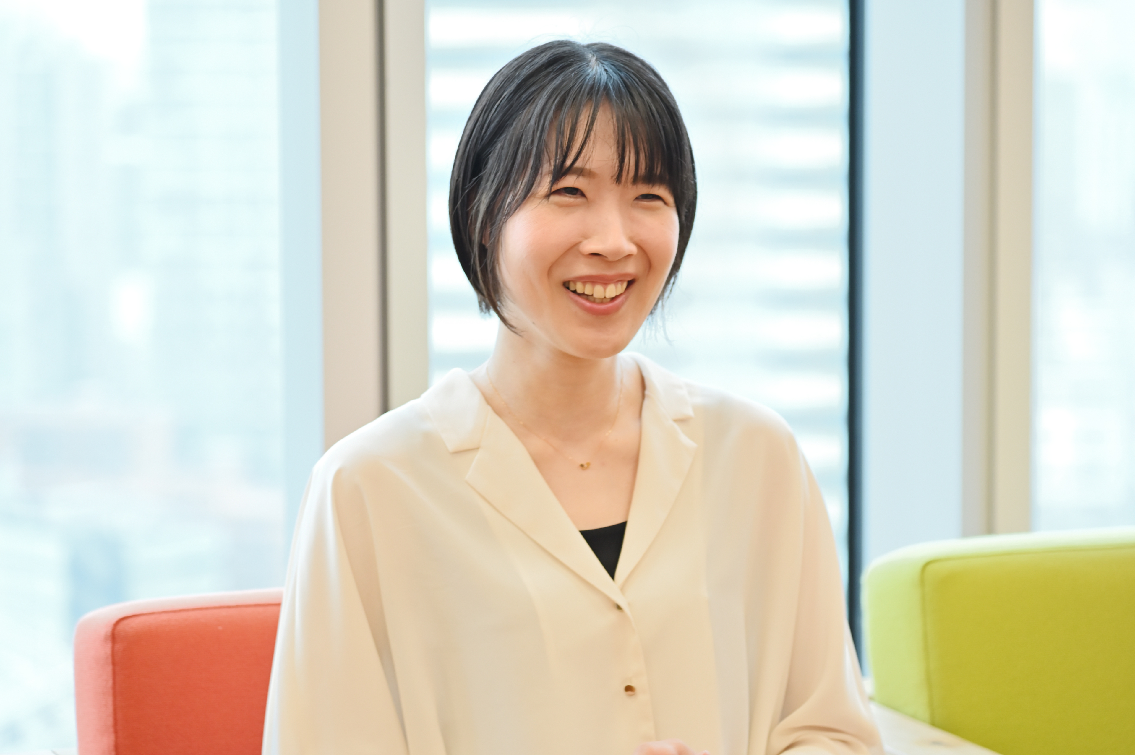 明るい空間のなか、ソファに座り笑顔でインタビューに答える女性